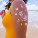 brown skin with sunscreen woman applying sun cream her body drawing with sun cream arm