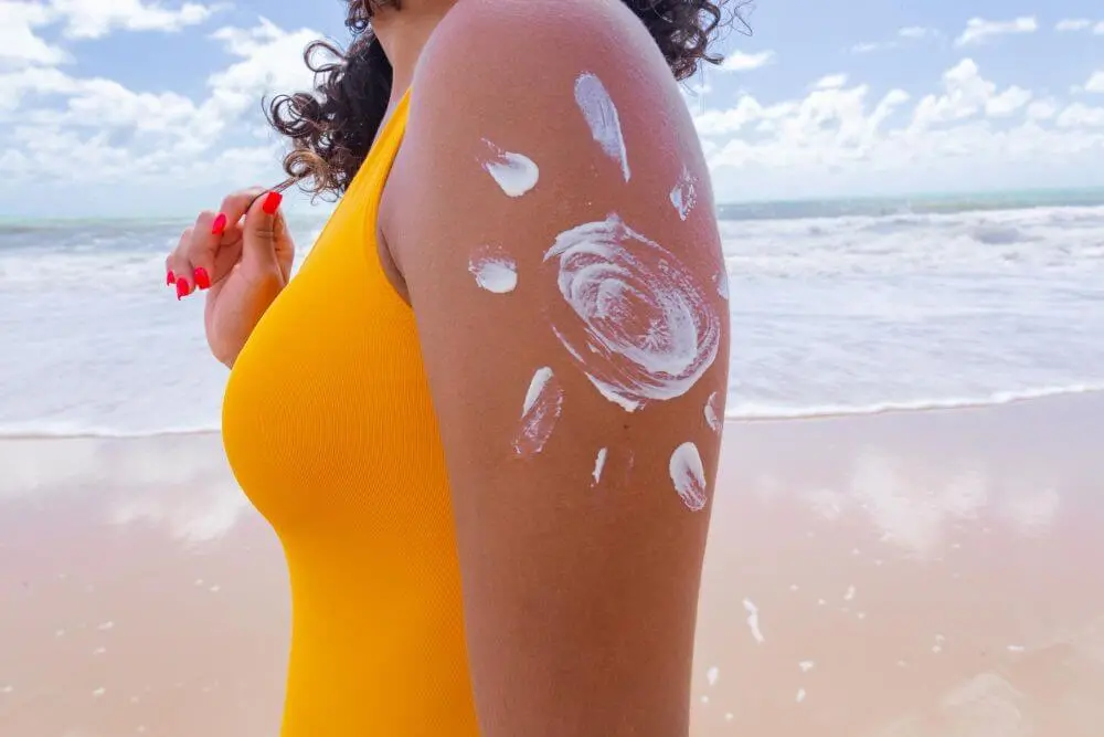 brown skin with sunscreen woman applying sun cream her body drawing with sun cream arm jpg