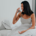 unhealthy sick indian female suffers from insomnia asian young woman taking painkiller medicine relieve headache pain drink glass water sitting bed her bedroom home morning 1 1