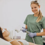 Uśmiechnięta kobieta podczas wykonywania zabiegu depilacji laserowej