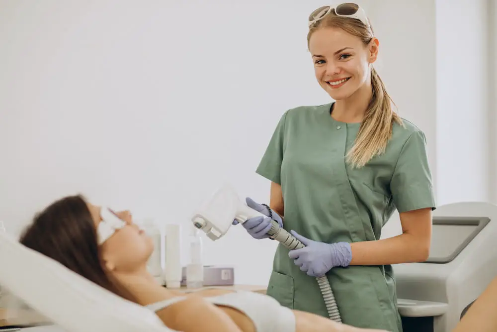 Uśmiechnięta kobieta podczas wykonywania zabiegu depilacji laserowej