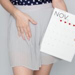 Kobieta trzyma w ręce kalendarz z zaznaczoną miesiączką
