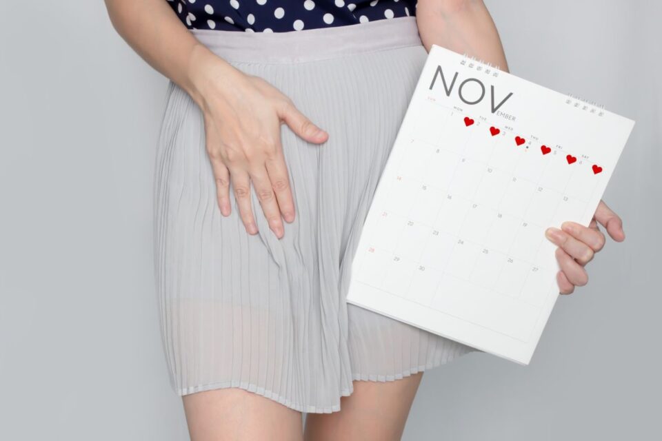 Kobieta trzyma w ręce kalendarz z zaznaczoną miesiączką